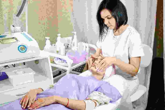 A woman is sitting on the bed while another person sits in front of her.