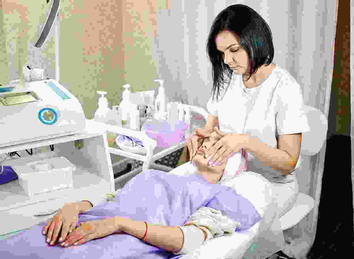 A woman is sitting on the bed while another person sits in front of her.