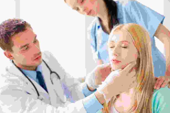 A doctor and two women are examining the neck of a young girl.
