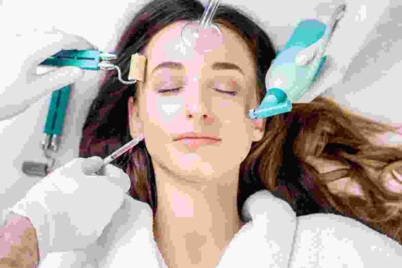 A woman is getting her face waxed by two hands.