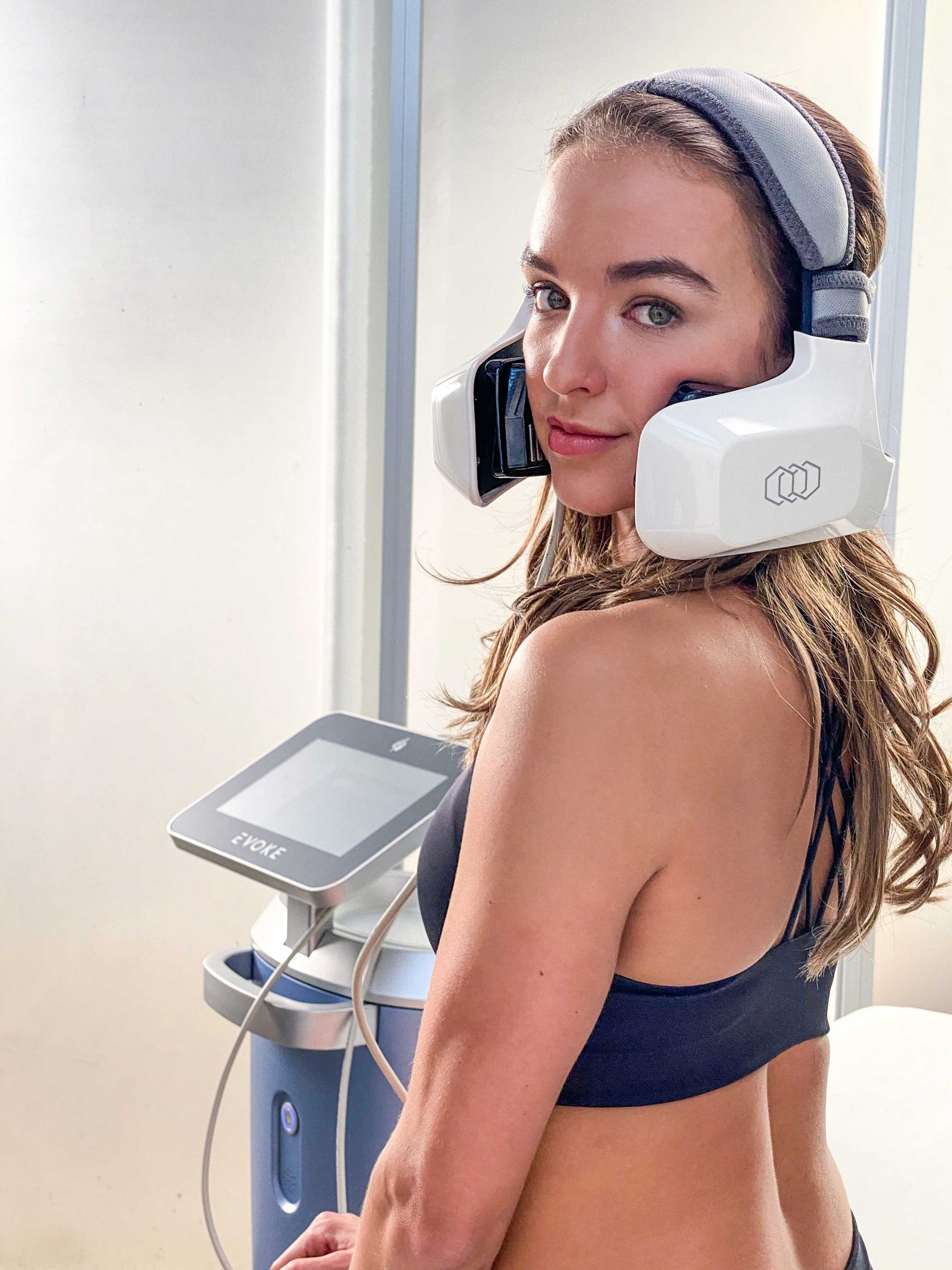 A woman with headphones on and holding onto a device