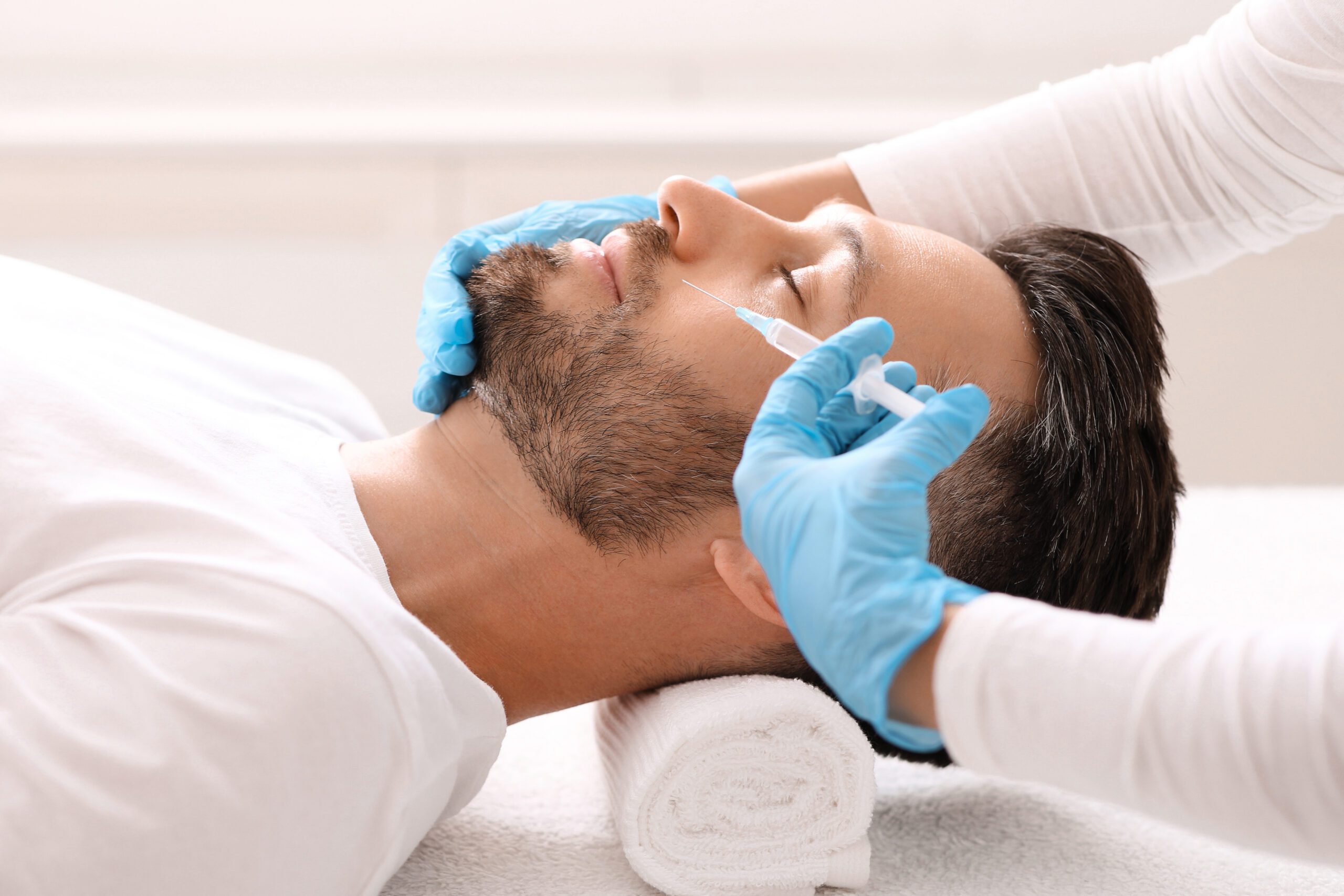 A man is getting his face cleaned by an esthetician.